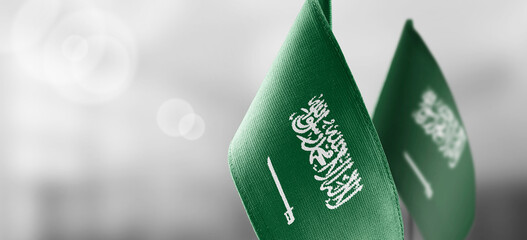 Small national flags of the Saudi Arabia on a light blurry background