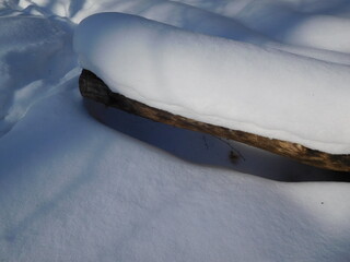 fluffy snow thickly covered a log in the forest in winter, close-up, winter season concept