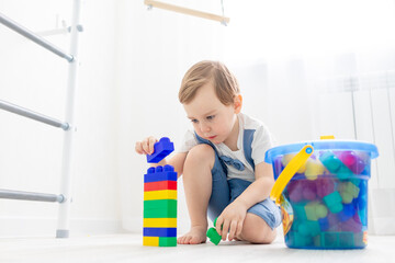 a child with a constructor at home, a cute boy plays or collects a colored constructor