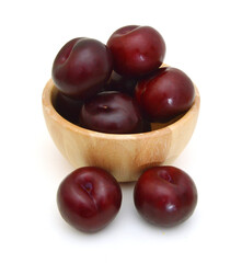 Red plum fruit isolated in wooden bowl on white background