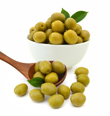 Green olives in white bowl with wooden spoon on a white background.