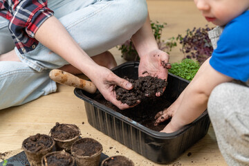Sensory activities for child - young mother and son playing with dirt prepared for seeds. At home gardening and learning botany concept.