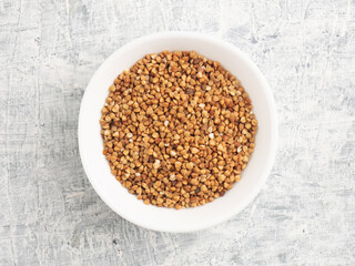 Buckwheat in a ceramic white cup on a white concrete background