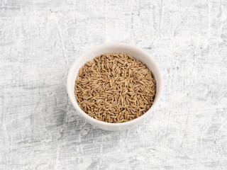 Spice cumin in ceramic bowl on a white concrete background