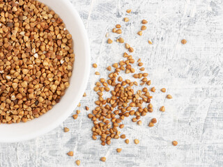 Buckwheat in a ceramic white cup on a white concrete background. Diet and weight loss concept