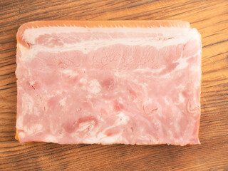 Piece of meat bacon on brown wooden cutting board