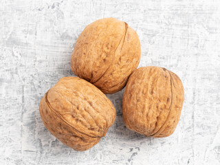 Three walnuts on white concrete background