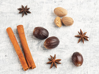 Nutmeg, cinnamon, star anise on white concrete background