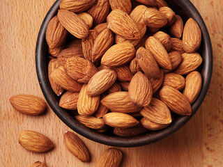 Almond in a bowl on wooden background with copy space