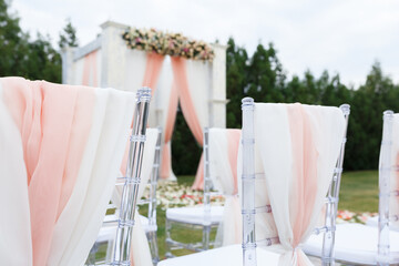 Place for wedding ceremony in white color .White square wedding arch with bouquets of pastel roses in the forest.