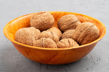 Walnuts in a bamboo bowl on gray concrete background