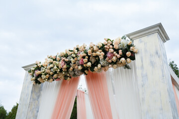 Fototapeta na wymiar Place for wedding ceremony in white color .White square wedding arch with bouquets of pastel roses in the forest.