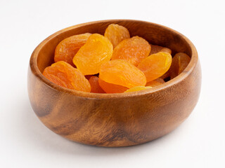 Dried apricots in wooden bowl on white. Healthy eating concept