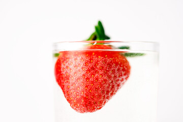 Strawberries in grall of water on white background. Advertising cocktails. Juicy fruits under water. Being shot as they submerged under water. A healthy form of product promotion.