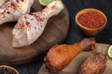 Close up photo of spicy raw chicken legs with lime on wooden board