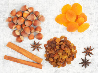 Cinnamon, star anise, dried apricots, raisins, nuts on white concrete background