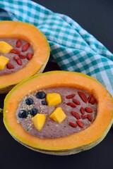 Melon bowl with berry smoothie topped with goji berry, mango, blueberry and hemp seeds
