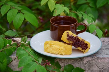 Kue Pukis, Traditional Javanese half-moon shaped pancakes. made from flour, eggs, yeast and coconut milk. Served with cup of tea. Leaves background