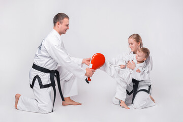 Young family with their little boy practicing martial arts over white background.