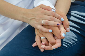 The newlyweds' hands are intertwined with each other, the bride's palm rests on top of the groom's hand.