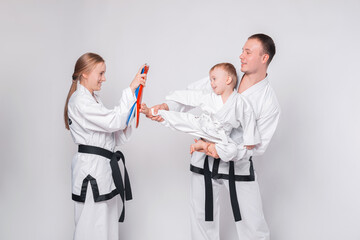 Young family with their little boy practicing martial arts over white background. © Vulp