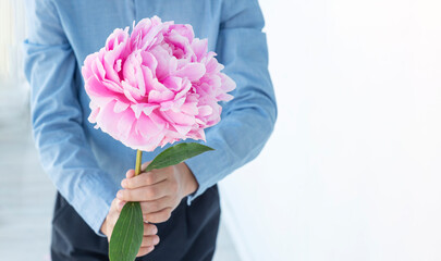 Boys hands hold huge gentle peony on white background. Copy space for text. Greetings concept. Congratulating with womans, mothers day, anniversary, birthday.