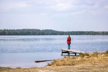 Girl in a red coat by the lake