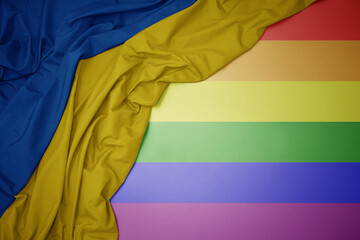 waving national flag of ukraine on a gay rainbow flag background.