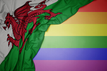 waving national flag of wales on a gay rainbow flag background.