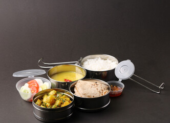Typical Stainless steel Lunch Box or Tiffin with Maharashtrian food menu Chapati OR Roti, Plain Dal Tadka, White Rice Potato sabji with salad and pickle