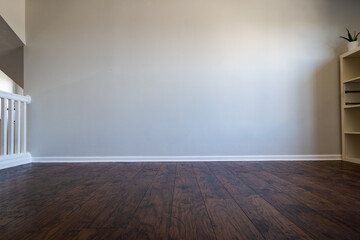 Empty room interior with laminated wood floor and gray wall. Bookshelf visible on the right side....