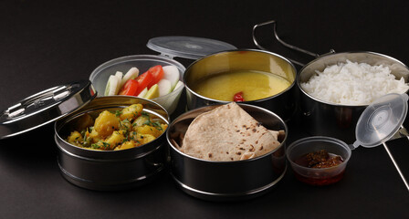 Typical Stainless steel Lunch Box or Tiffin with Maharashtrian food menu Chapati OR Roti, Plain Dal Tadka, White Rice Potato sabji with salad and pickle