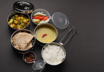Typical Stainless steel Lunch Box or Tiffin with Maharashtrian food menu Chapati OR Roti, Plain Dal Tadka, White Rice Potato sabji with salad and pickle