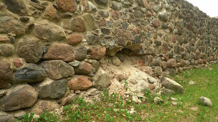 View to a large stone wall with traces of a cannonball shot in a territory of Dobele Castle ruins. Impressive medieval century architecture sample from big boulders in Latvia country, Europe.
