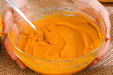 Fresh pumpkin puree in a glass bowl close up on rustic background. Making pumpkin puree from scratch