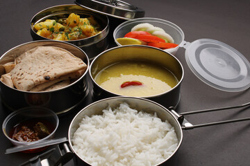 Typical Stainless steel Lunch Box or Tiffin with Maharashtrian food menu Chapati OR Roti, Plain Dal Tadka, White Rice Potato sabji with salad and pickle