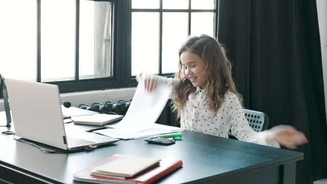 Happy but Tired little female boss throwing office papers, documents and diagrams, ready to have a break or vacation. Stop working. Happy businesswoman  is excited to finish a working day
