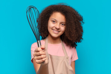pretty afro teenager girl cooking with an apron and a mixer. baker concept