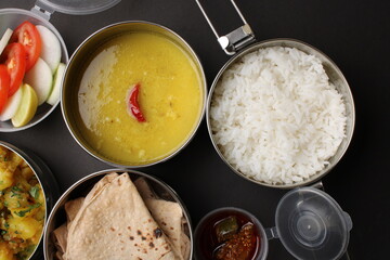 Typical Stainless steel Lunch Box or Tiffin with Maharashtrian food menu Chapati OR Roti, Plain Dal Tadka, White Rice Potato sabji with salad and pickle