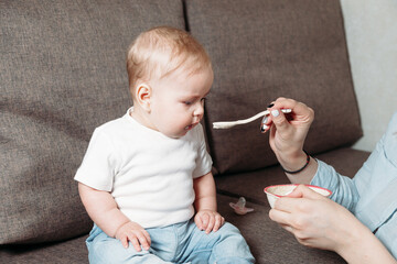 young mother feeds her son with a spoon of fruit puree