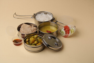 Typical Stainless steel Lunch Box or Tiffin with Maharashtrian food menu Chapati OR Roti, Plain Dal Tadka, White Rice Potato sabji with salad and pickle