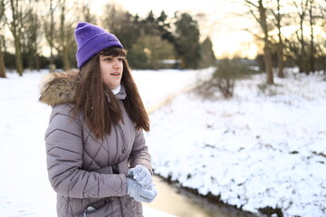 happy child girl playing with snow, throwing snowball on winter snowy walk in park, seasonal outdoor activities, copy space