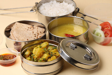 Typical Stainless steel Lunch Box or Tiffin with Maharashtrian food menu Chapati OR Roti, Plain Dal Tadka, White Rice Potato sabji with salad and pickle