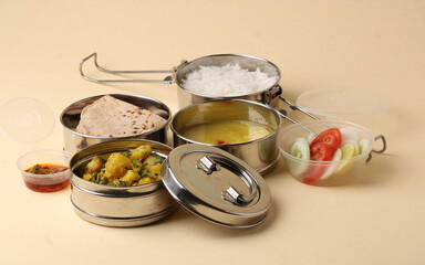 Typical Stainless steel Lunch Box or Tiffin with Maharashtrian food menu Chapati OR Roti, Plain Dal Tadka, White Rice Potato sabji with salad and pickle