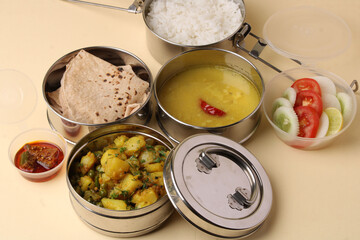 Typical Stainless steel Lunch Box or Tiffin with Maharashtrian food menu Chapati OR Roti, Plain Dal Tadka, White Rice Potato sabji with salad and pickle