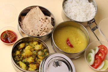 Typical Stainless steel Lunch Box or Tiffin with Maharashtrian food menu Chapati OR Roti, Plain Dal Tadka, White Rice Potato sabji with salad and pickle