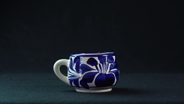 A closeup of a ceramic Talavera cup isolated on a black background