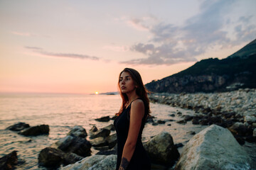 Pretty brunette girl looking at sunset on sea 
