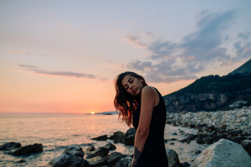 Pretty brunette girl looking at sunset on sea 