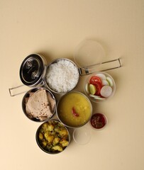 Typical Stainless steel Lunch Box or Tiffin with Maharashtrian food menu Chapati OR Roti, Plain Dal Tadka, White Rice Potato sabji with salad and pickle